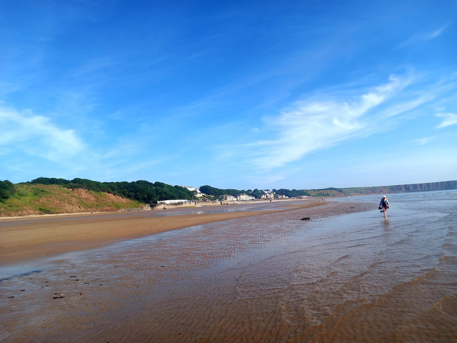 Filey beach with the cliffs and town in the distance on a sunny day
